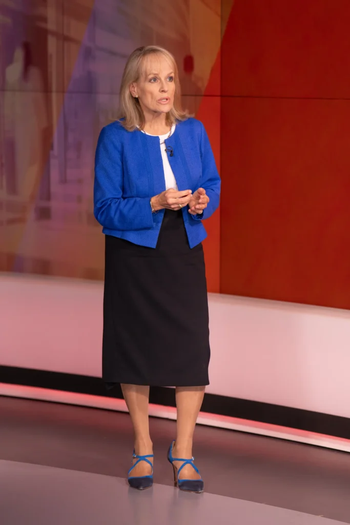 Presenter in a blue jacket delivering a health segment on a red-lit TV studio set
